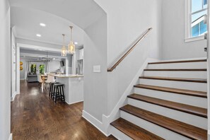 A modern kitchen with a central island, wooden staircase, and a dining area with a view of the outdoors. - Fully Furnished 3BR East Nashville Home | 30+ Days (Nashville)
