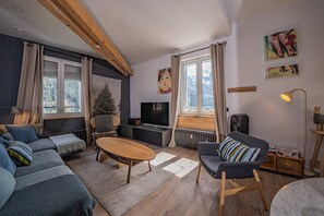 A modern living room with a sofa, a coffee table, a TV, and a fireplace. - Majestic Panorama - Stunning Mont Blanc Views|Fireplace|Central Chamonix (Chamonix-Mont-Blanc)