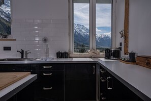 Eine moderne Küche mit Blick auf verschneite Berggipfel durch große Fenster.