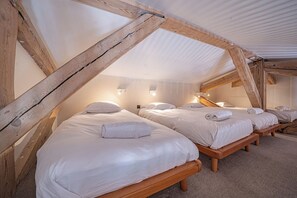 A room with three wooden beds arranged in a row, each with a pillow and a rolled towel. - Majestic Panorama - Stunning Mont Blanc Views|Fireplace|Central Chamonix (Chamonix-Mont-Blanc)