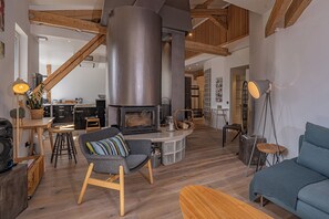 Ein gemütliches Wohnzimmer mit Kamin, Holzbalken und einem modernen Sofa.