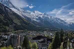 A town nestled between snow-capped mountains with a mix of residential buildings and greenery. - Majestic Panorama - Stunning Mont Blanc Views|Fireplace|Central Chamonix (Chamonix-Mont-Blanc)