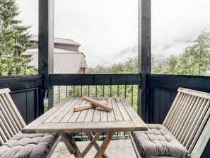A wooden deck with a table and two cushioned chairs, overlooking a mountainous landscape. - Marmottons - Comfortable 2-bedroom apartment (Chamonix-Mont-Blanc)