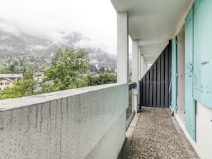 Un balcon avec un sol en béton et une vue sur une montagne et des bâtiments en arrière-plan.