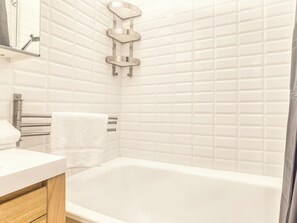 A bathroom with a white bathtub, a towel rack, and a mirror. - Marmottons - Comfortable 2-bedroom apartment (Chamonix-Mont-Blanc)