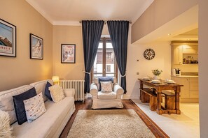 A cozy living room with a sofa, a coffee table, and a dining area with a wooden table and benches. - Pointe Lachenal - Beautifully furnished apartment in the heart of Chamonix (Chamonix-Mont-Blanc)