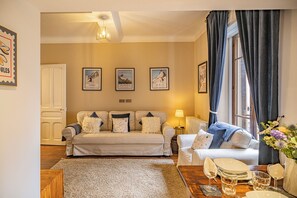 A cozy living room with a sofa set, a dining table with chairs, and a large window with curtains. - Pointe Lachenal - Beautifully furnished apartment in the heart of Chamonix (Chamonix-Mont-Blanc)