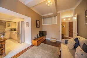 A modern living space with a kitchen, dining area, and a cozy seating area with a TV and decorative items. - Pointe Lachenal - Beautifully furnished apartment in the heart of Chamonix (Chamonix-Mont-Blanc)