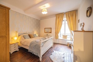 A bedroom with a bed, bedside tables, a dresser, a window with curtains, and a radiator. - Pointe Lachenal - Beautifully furnished apartment in the heart of Chamonix (Chamonix-Mont-Blanc)