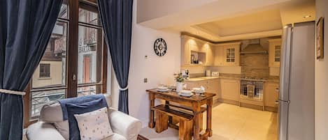 A living room with a sofa, a dining table, and a kitchen area with a refrigerator and stove.