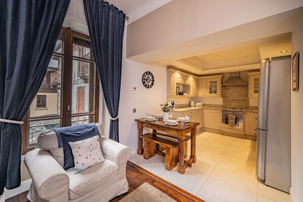 A living room with a sofa, a dining table, and a kitchen area with a refrigerator and stove. - Pointe Lachenal - Beautifully furnished apartment in the heart of Chamonix (Chamonix-Mont-Blanc)