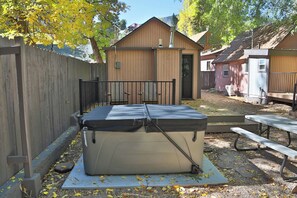 A portable mattress on a mat, a picnic table, and a wooden fence in a backyard setting. - NEW! On The Creek. Cozy. 1 BR 1 BA Cabin. Downtown Manitou Springs. New Hot Tub! (Manitou Springs)