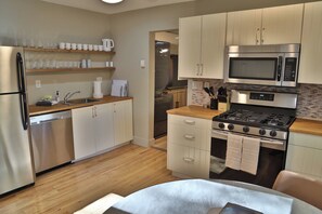 A modern kitchen with stainless steel appliances, wooden countertops, and a built-in oven. - NEW! On The Creek. Cozy. 1 BR 1 BA Cabin. Downtown Manitou Springs. New Hot Tub! (Manitou Springs)
