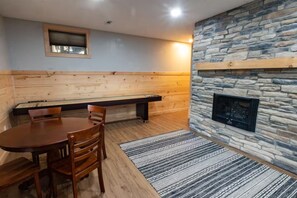 A room with a stone fireplace, wooden bench, and a round table with chairs.