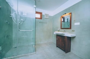 A bathroom with a glass shower enclosure, a sink with a wooden cabinet, and a mirror with a wooden frame. - Villa Sewinro – Comfortable Family Stay Near Talpe Beach. (Habaraduwa)