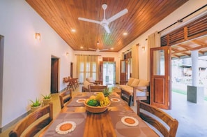 A dining area with a wooden table, chairs, and a ceiling fan. - Villa Sewinro – Comfortable Family Stay Near Talpe Beach. (Habaraduwa)