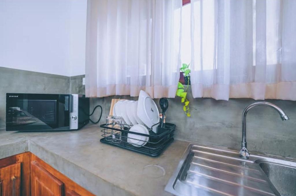 Cozinha equipada com micro-ondas, escorredor de louça e pia.