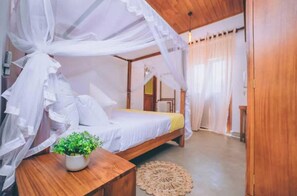 A bedroom with a canopy bed, a bedside table with a plant, and a wooden floor. - Villa Sewinro – Comfortable Family Stay Near Talpe Beach. (Habaraduwa)