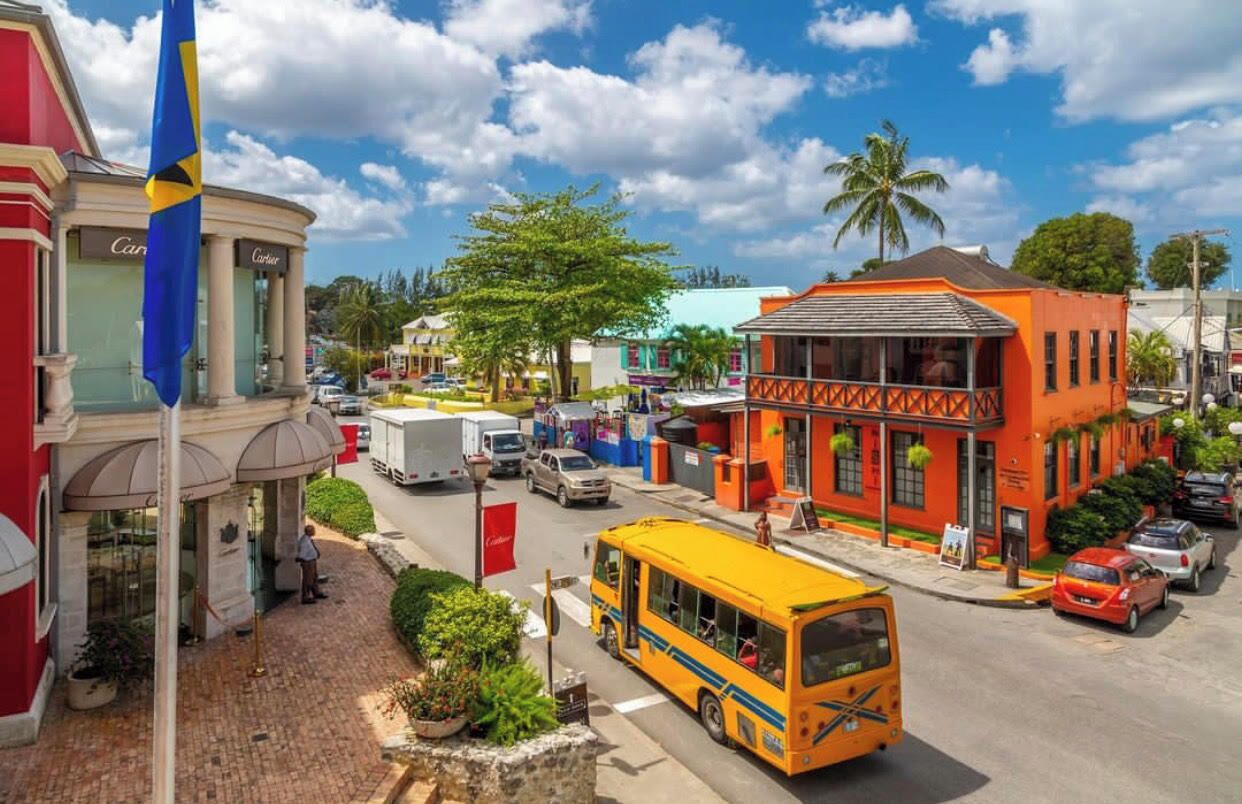 A street view with a yellow bus, a red building, and a blue flag.