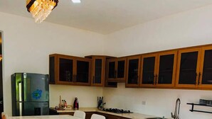 Cozinha moderna com bancada de mármore, armários de madeira e área de jantar com cadeiras.