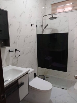 A bathroom with a toilet, sink, and shower area.