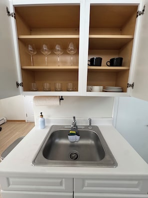 A kitchen with a stainless steel sink, a soap dispenser, and a colander.