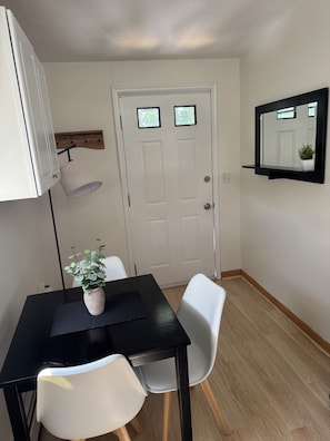 A room with a black table, white chairs, a potted plant, a white door, and a wall-mounted mirror. - Newly Renovated 1BR – 5 Minutes to Valhalla Train, White Plains, WMC & NYC (White Plains)