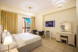 Ein Hotelzimmer mit Bett, Schreibtisch, Stuhl, Schminktisch und Blick auf die Stadt.