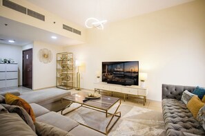 Ein modernes Wohnzimmer mit Flachbildfernseher, Sofas, einem Couchtisch und einem dekorativen Regal.