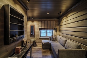 A cozy cabin interior with a wooden wall, a sofa, a small table, and a window with a view. - Vågå vertshus (Innlandet)