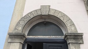 Un arco de piedra con la inscripción 'GOSPEL HALL' sobre una puerta negra.