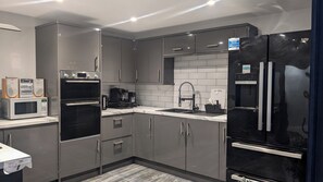 Una cocina moderna con horno integrado, microondas, cafetera y refrigerador negro.
