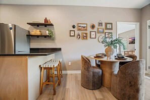 A modern kitchen with a built-in refrigerator, wooden stools, a round dining table with chairs, and a variety of framed pictures on the wall. - Sevierville Cabin Near Dollywood, Sleeps 6, Hot Tub (Sevierville)