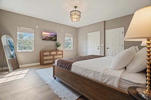 Une chambre à coucher avec un lit, une commode, une télévision et une lampe.