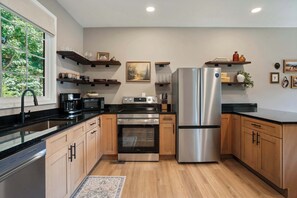 Une cuisine moderne dotée d’appareils électroménagers en acier inoxydable, de meubles en bois et d’une grande fenêtre.