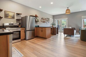 A modern kitchen with stainless steel appliances, wooden cabinets, and a dining area with a sofa and chairs. - Sevierville Cabin Near Dollywood, Sleeps 6, Hot Tub (Sevierville)