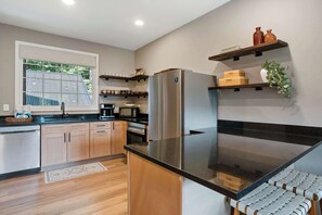 A modern kitchen with wooden cabinets, a stainless steel refrigerator, a microwave, and a coffee maker. - Sevierville Cabin Near Dollywood, Sleeps 6, Hot Tub (Sevierville)