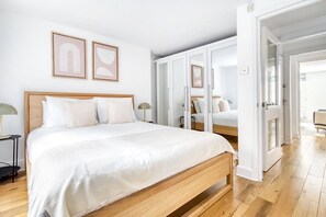 Een slaapkamer met een groot bed, een kledingkast en een spiegel.