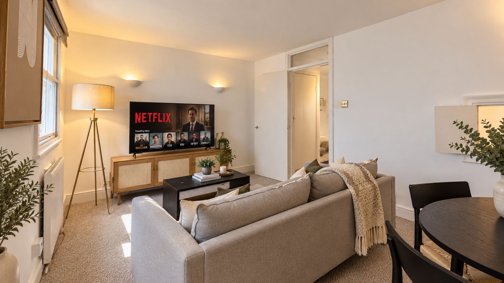 Sala de estar moderna com sofá, mesa de centro e televisão exibindo um programa da Netflix.