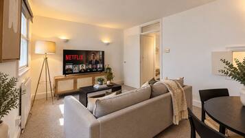 A modern living room with a sofa, coffee table, and a television displaying a Netflix show.
