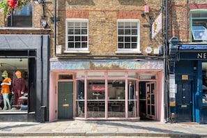 A corner building with a pink storefront, a visible entrance, and a sign for 'Redemption.' - Elegant Covent Garden 1BR Apartment | AC | near Soho, Oxford Street (London)