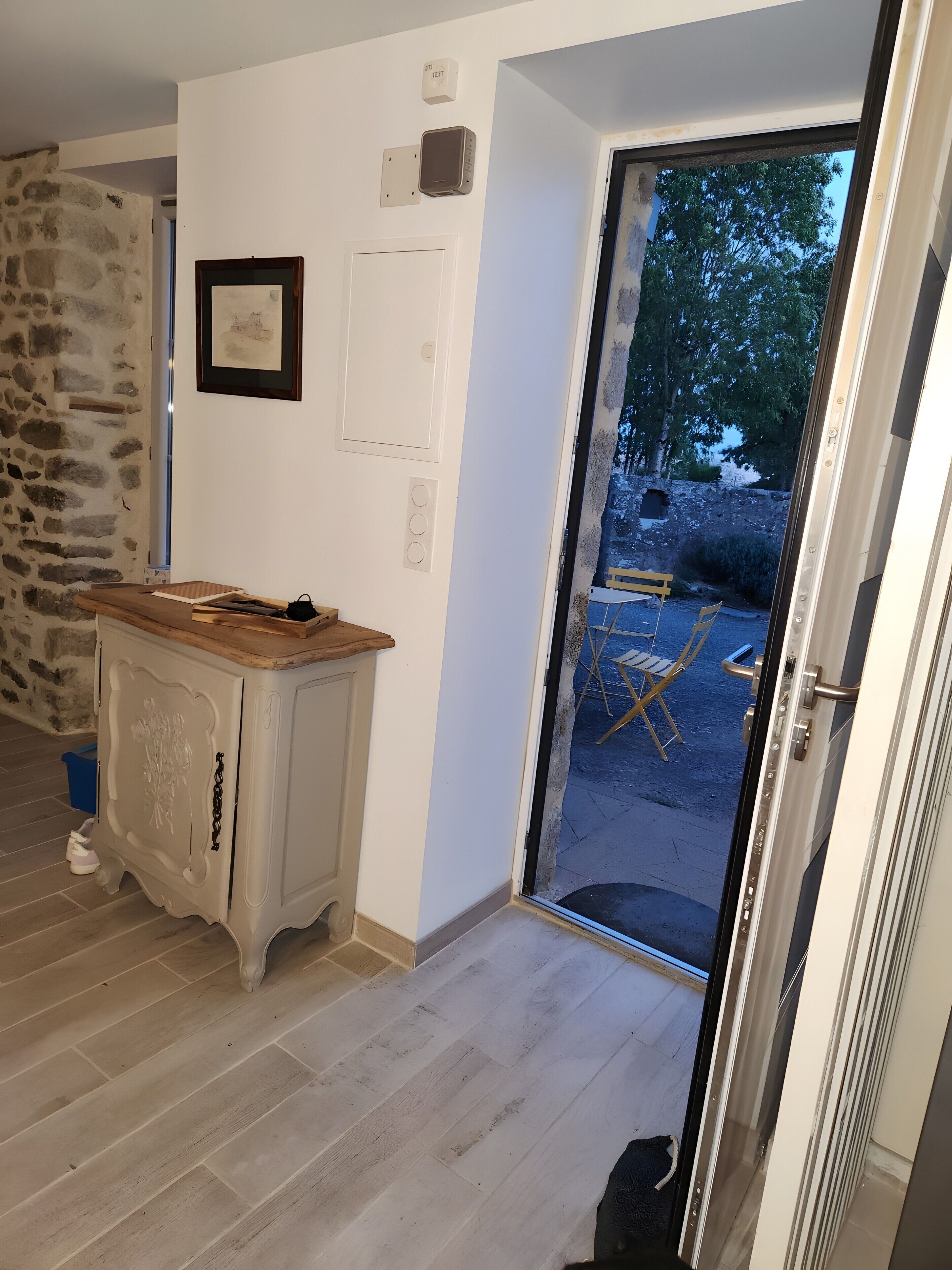 Ein Zimmer mit einem Holzkabinett, einer zur Außenseite führenden Tür und einer Steinwand.