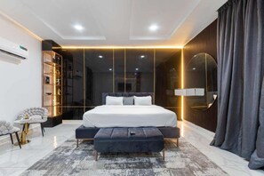 A modern bedroom with a large bed, bedside tables, a wardrobe, and a mirror. - Shu Garden Hotel (Lagos)