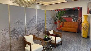 A room with a traditional Asian-style mural, two wooden chairs, a modern sofa, and a yellow vase. - Shu Garden Hotel (Lagos)