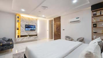 Un dormitorio moderno con una cama grande, un televisor montado en la pared y un estante empotrado con objetos decorativos.