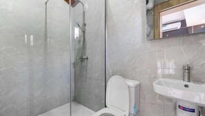 Un baño con ducha de vidrio, inodoro y lavamanos.
