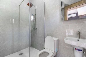 A bathroom with a glass-enclosed shower, a toilet, and a sink. - Shu Garden Hotel (Lagos)