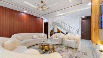 Una sala de estar moderna con un sofá modular, una mesita de centro y una escalera que conduce a un nivel superior.