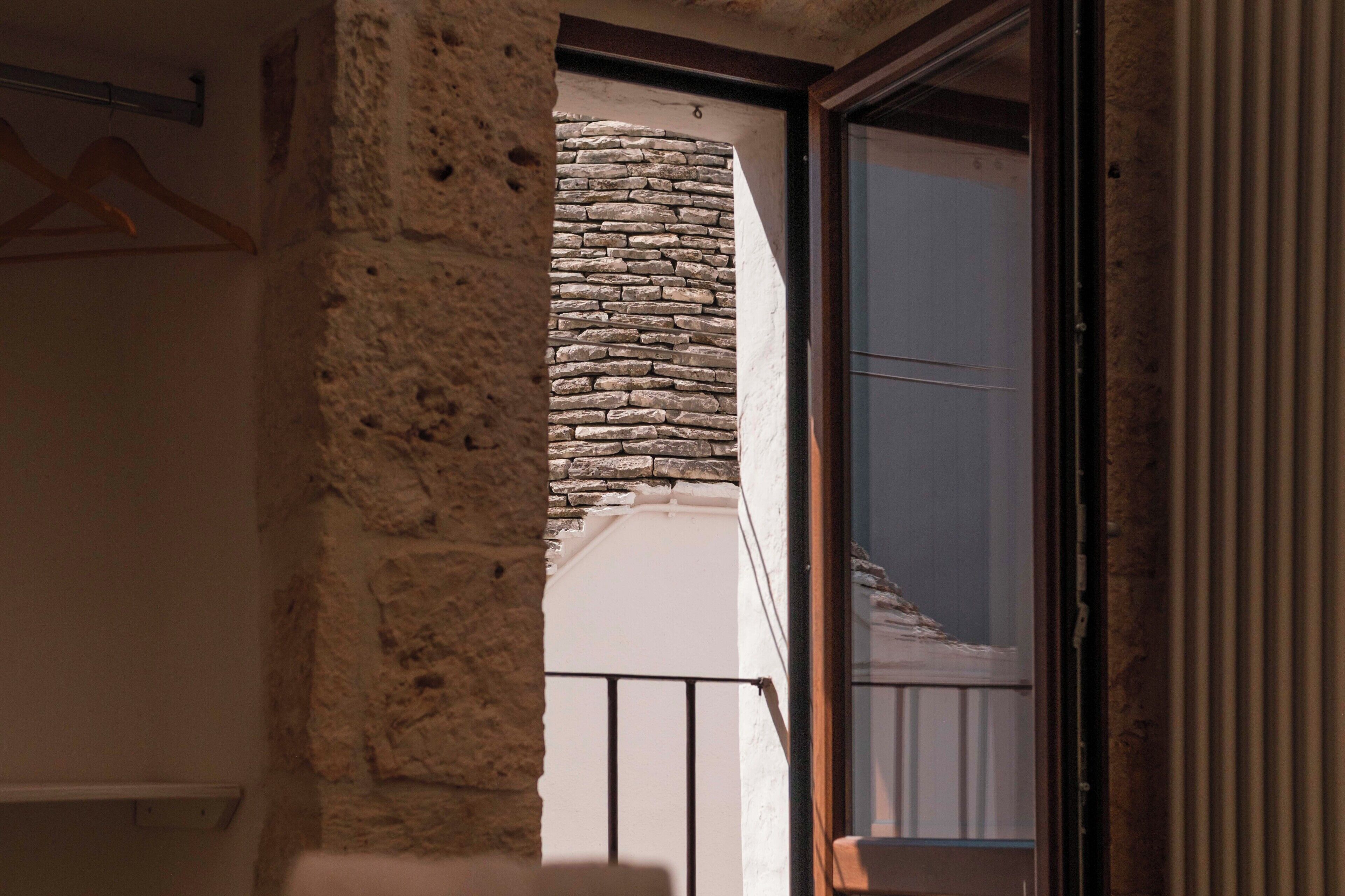 A stone wall with a balcony, a door, and a window.