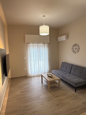 Un saló amb un sofà, una taula de centre, un rellotge penjat a la paret i un ventilador de sostre.
